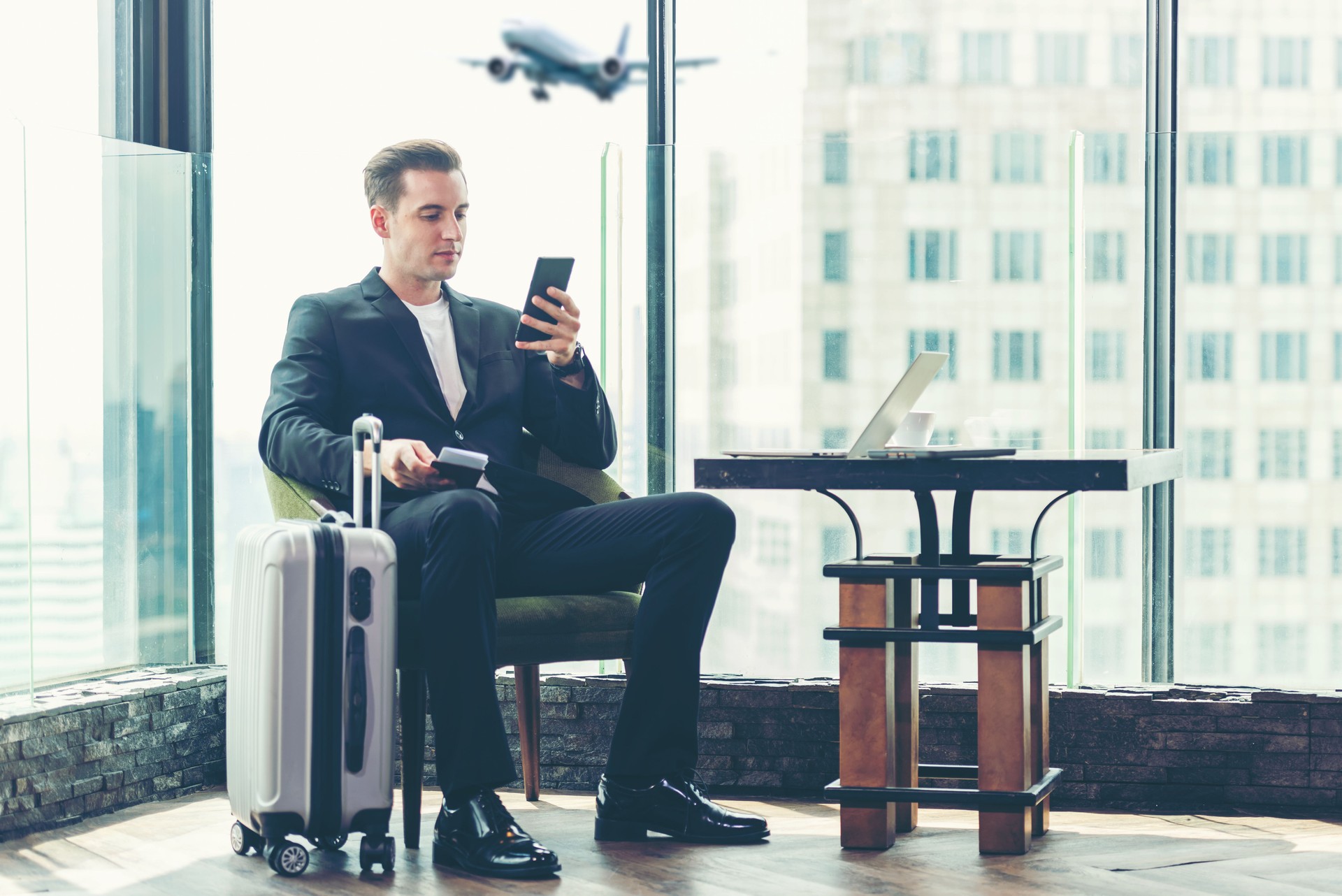 Businessman holding passport and  using smartphone check in air ticket  and boarding card in Departure Lounge at terminal airport.